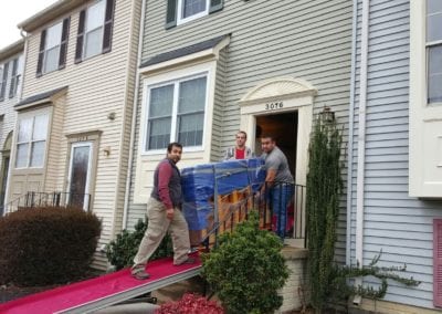 Men moving upright piano out of front door